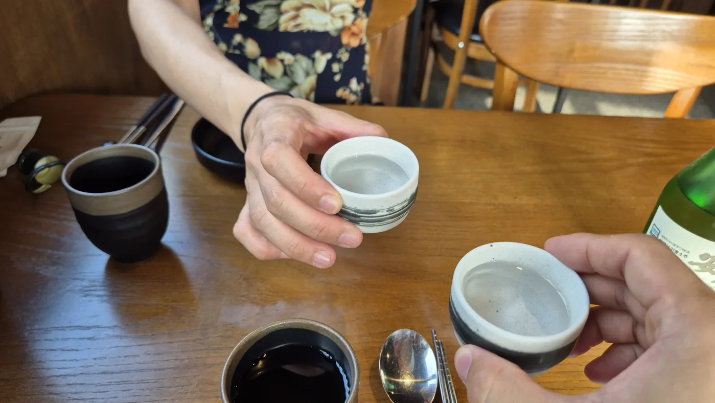 A respectful Korean drink-pouring moment at the shared dinner table